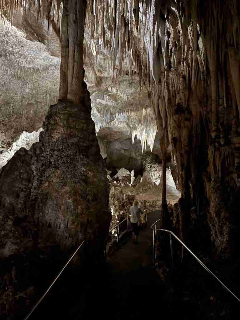 A woman walks between cave formations on the Big Room Trail in Carlsbad Caverns