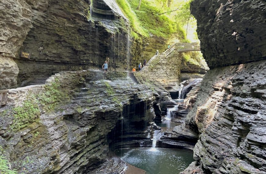 Julie waving from behind a waterfall in Watkins Glen
