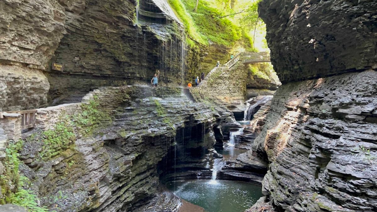 Julie waving from behind a waterfall in Watkins Glen