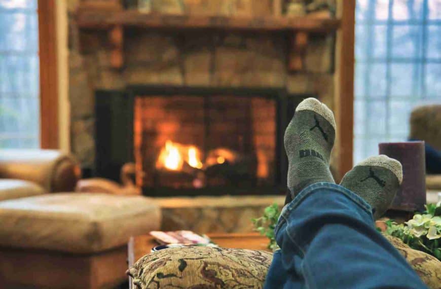 A person stretches their legs, relaxing by a warm fire in winter