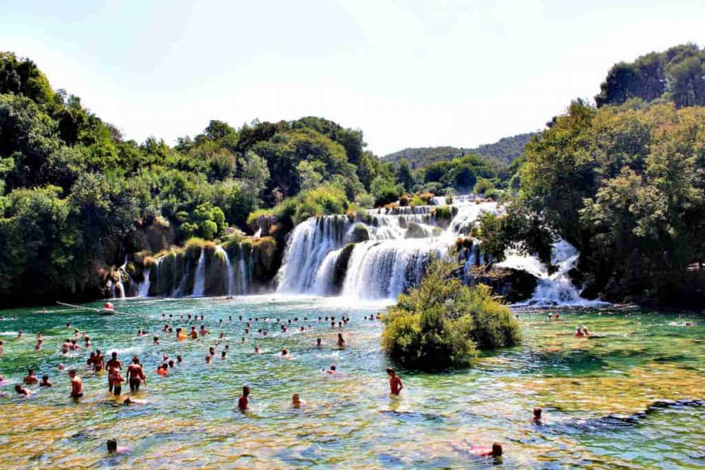 people on body of water with waterfalls during daytime