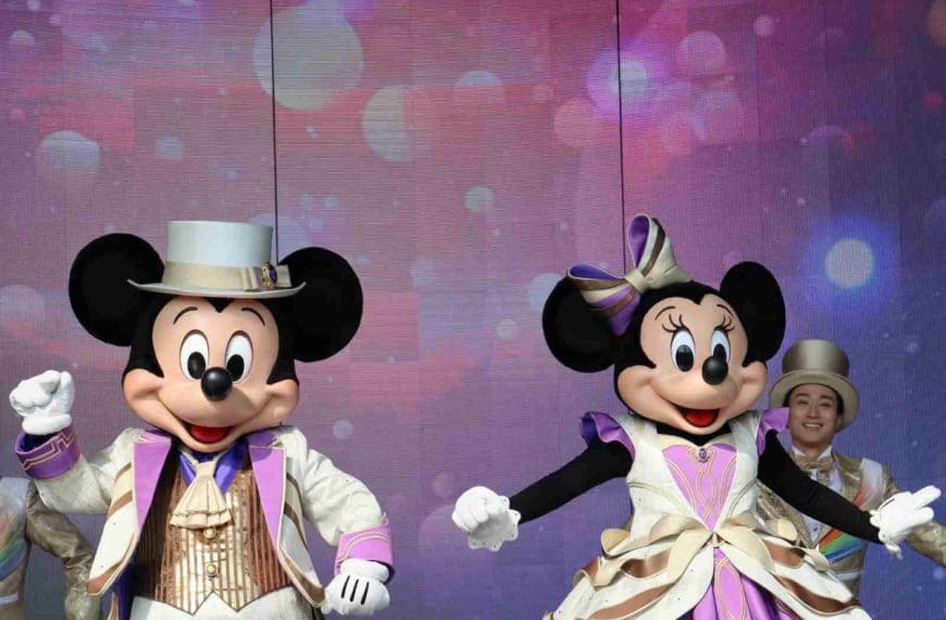 a couple of people that are standing in front of mickey mouse