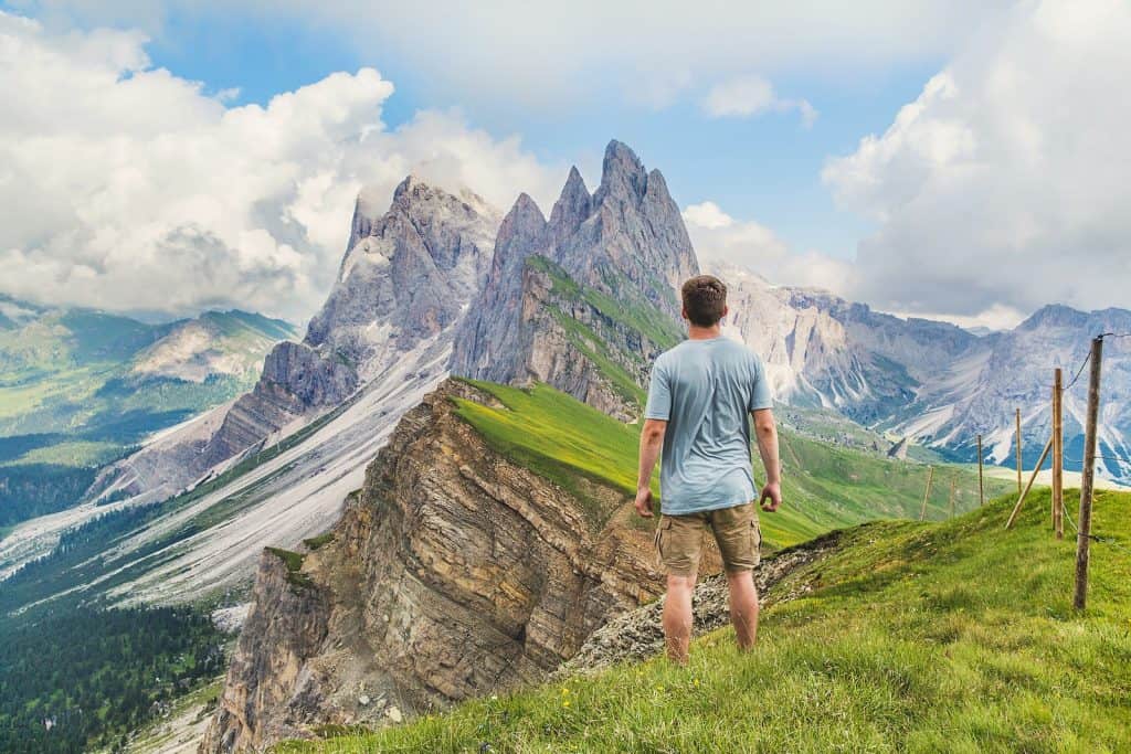 man in blue T-shirt on top of the mountain under the blue sky