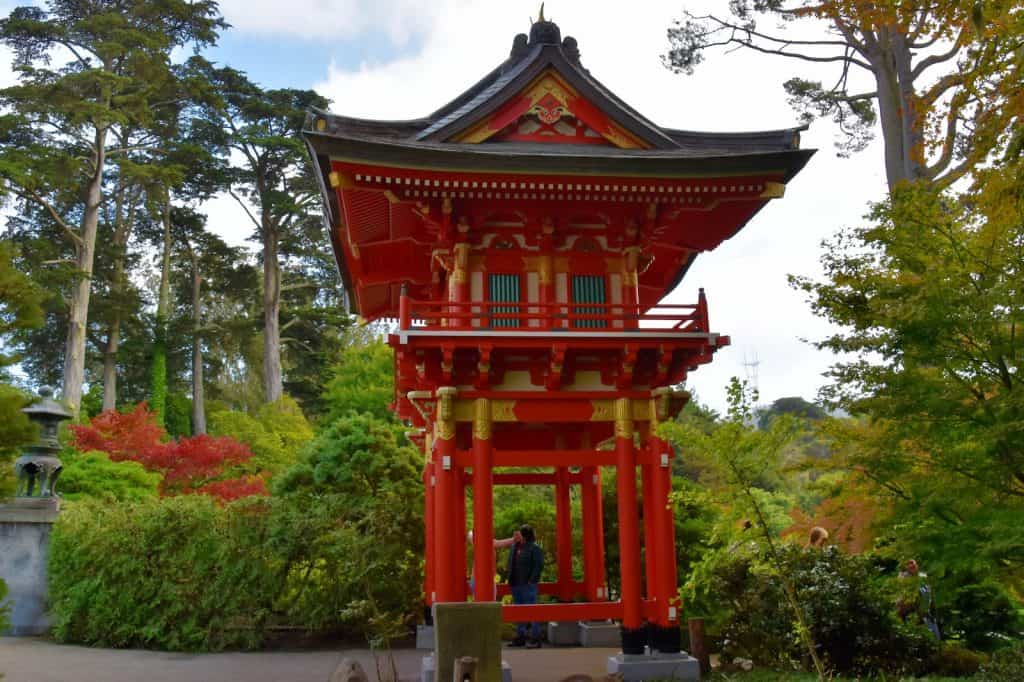 a tall red pagoda with a man standing in front of it