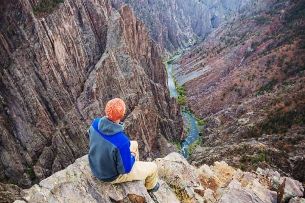 A tourist looks down into the canyon at Black Canyon of the Gunnison National Park, CO.