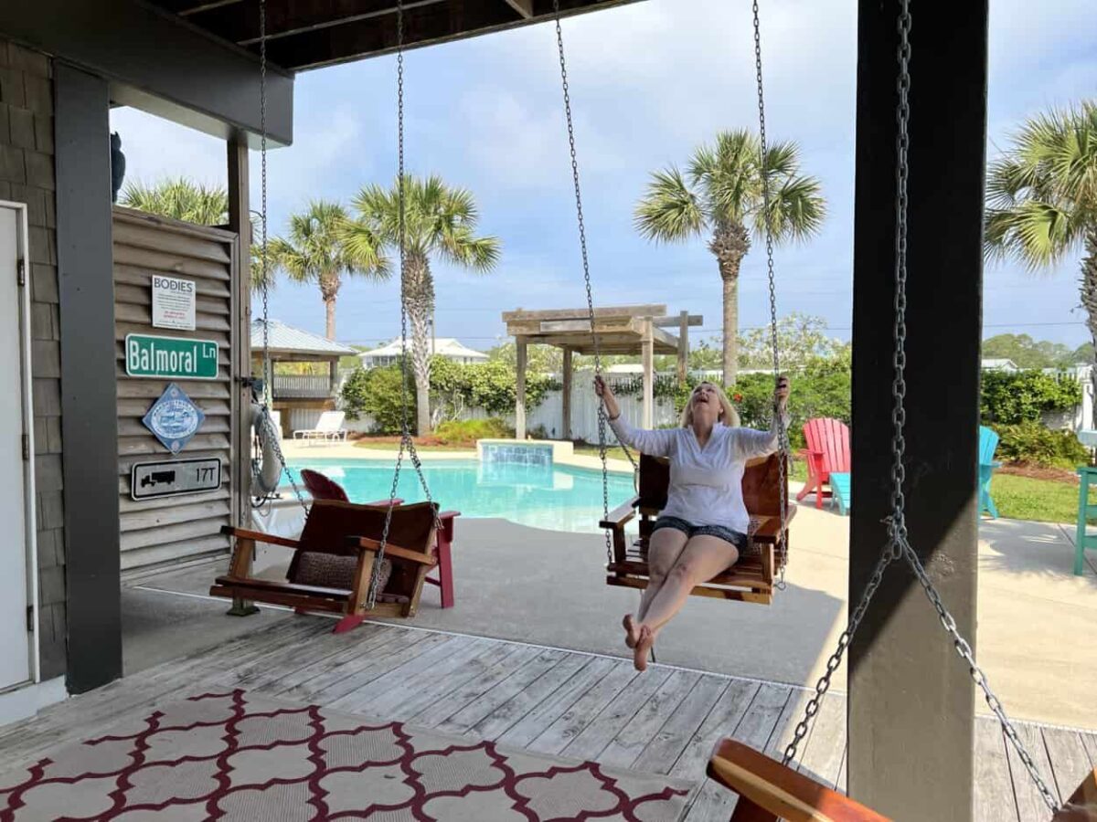 Julie McConkey of the Miles with McConkey Travel Blog sits on a porch swing at a vacation rental house in St. George Island.