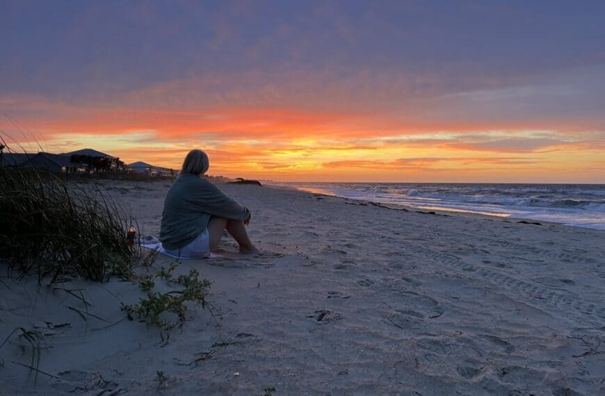 A woman watches sunrise at St. George Island, FL.