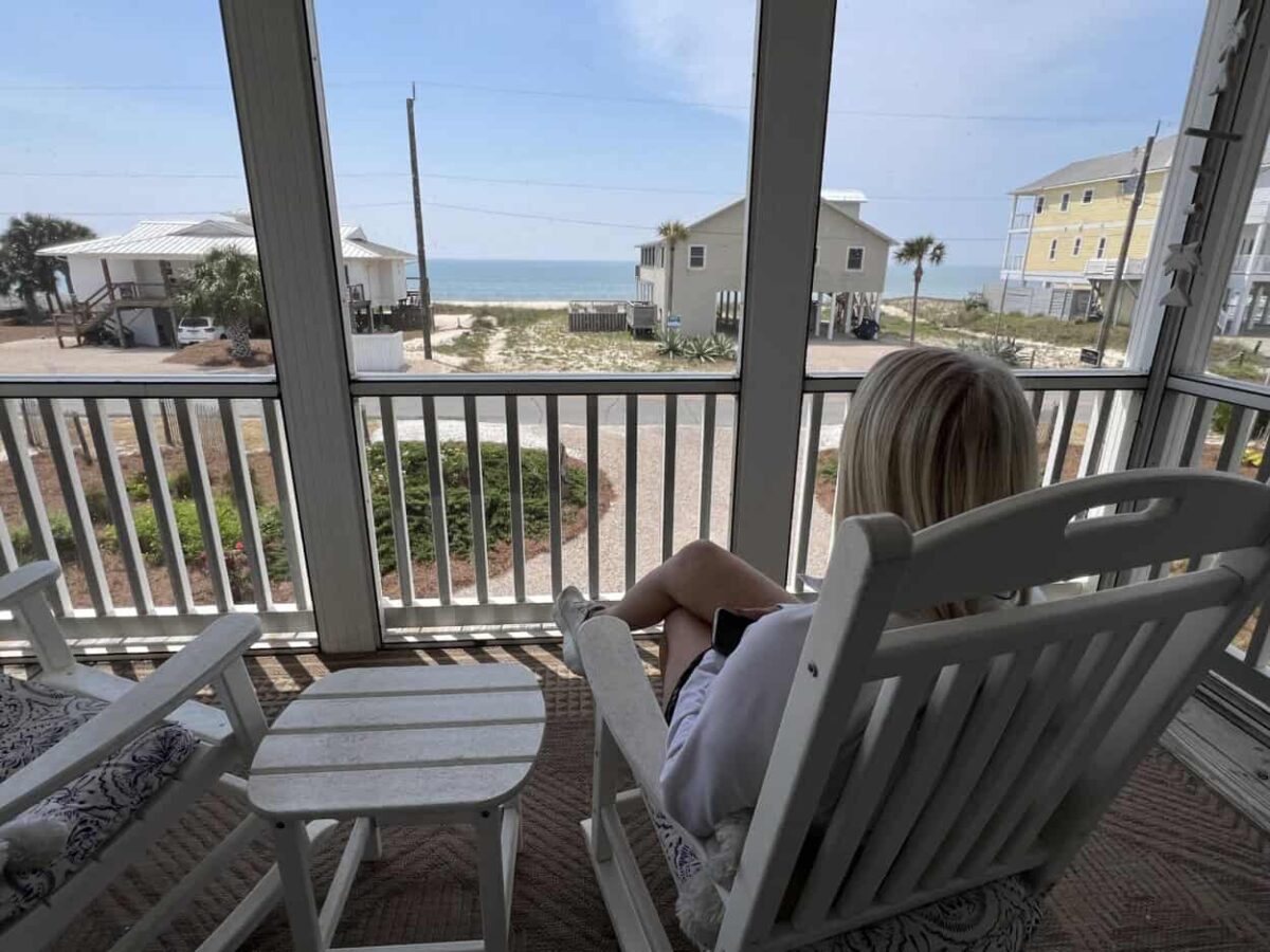 Julie sits in a rocking chair on the porch of our vacation rental at St. George Island.