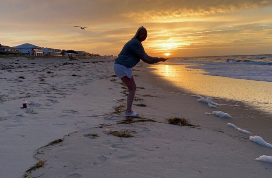 Julie pretends to hold the sun in her cupped hands during sunrise on St. George Island.