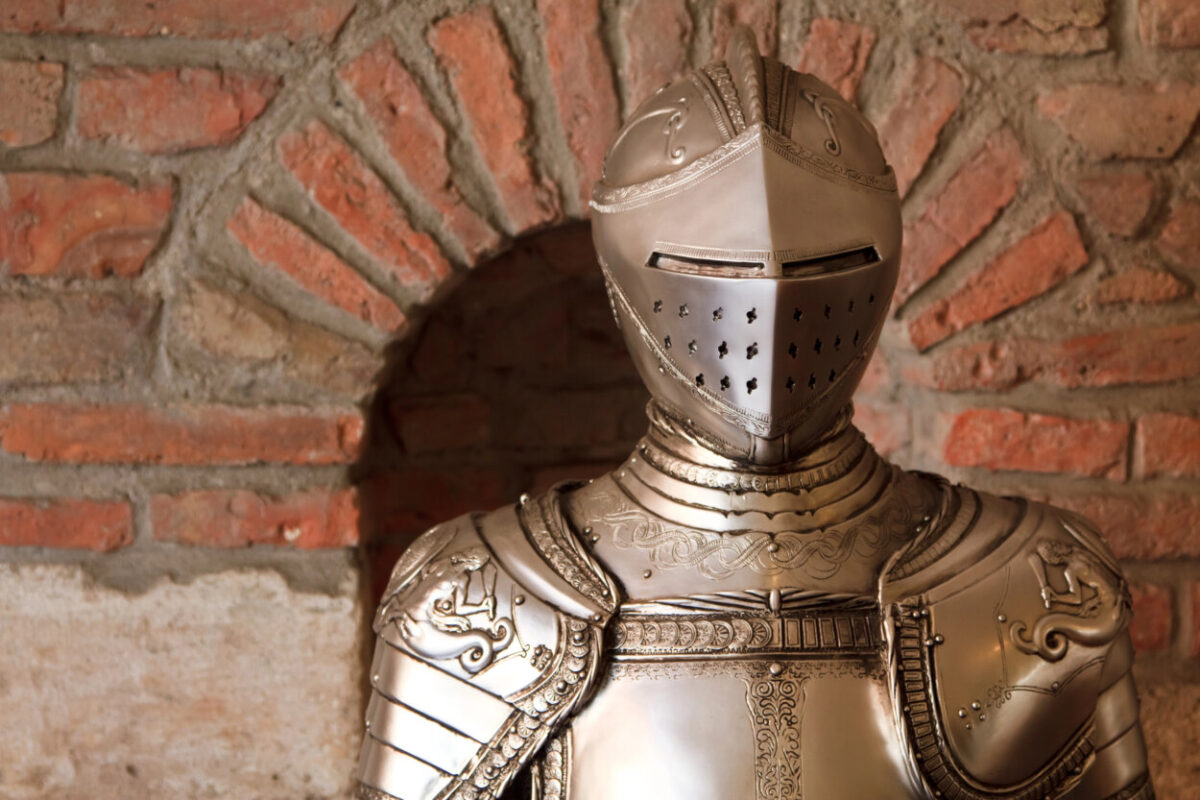 A suit of armor stands against a brick wall