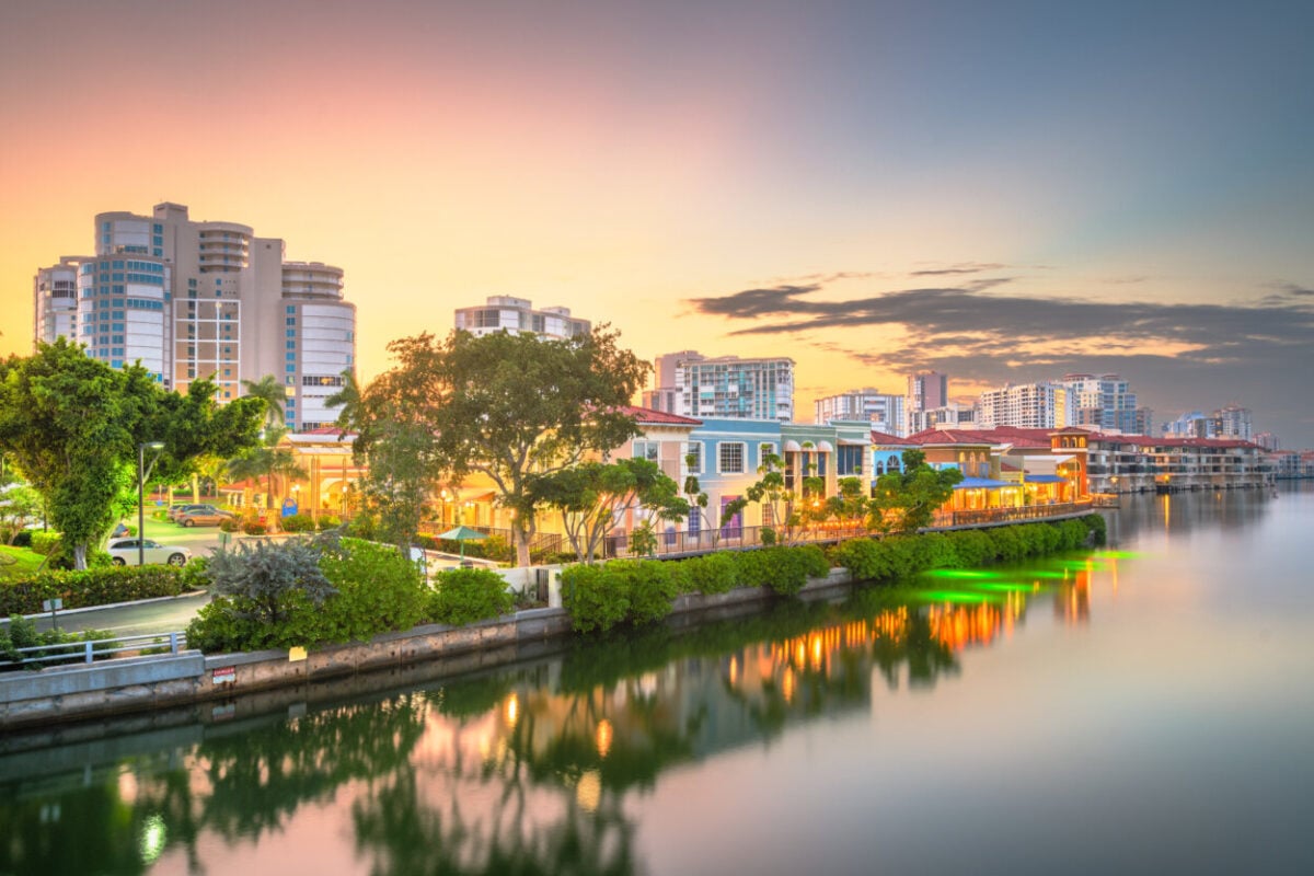 Buildings reflect in the water at dusk in Naples, FL