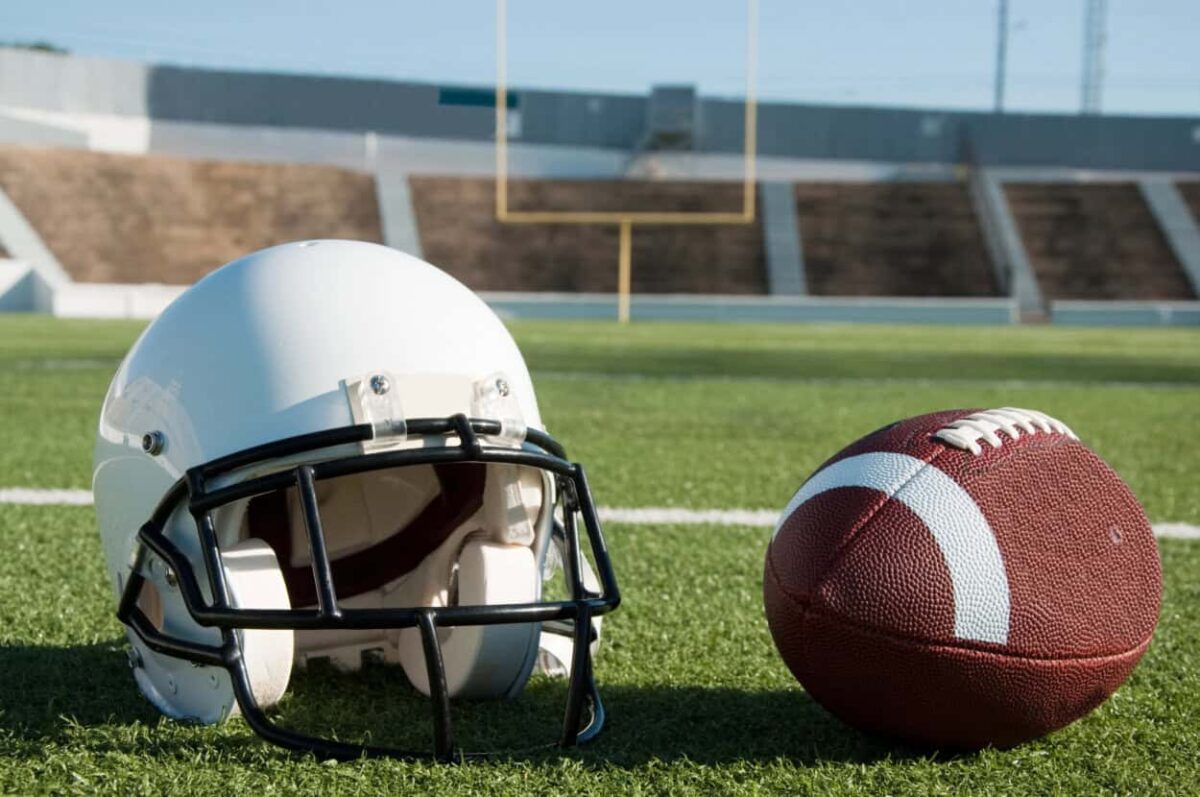 Football helmet and football sitting on a football field