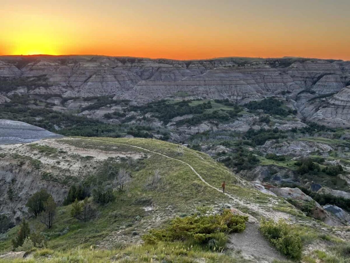 Scott McConkey, travel writer and founder of the Miles with McConkey Travel Blog, hikes a trail at sunrise in Theodore Roosevelt National Park North Unit