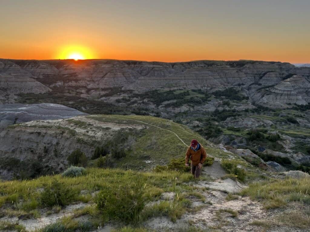 Scott McConkey, travel writer and founder of the Miles with McConkey Travel Blog, climbs a hill at sunrise in Theodore Roosevelt National Park, North Dakota