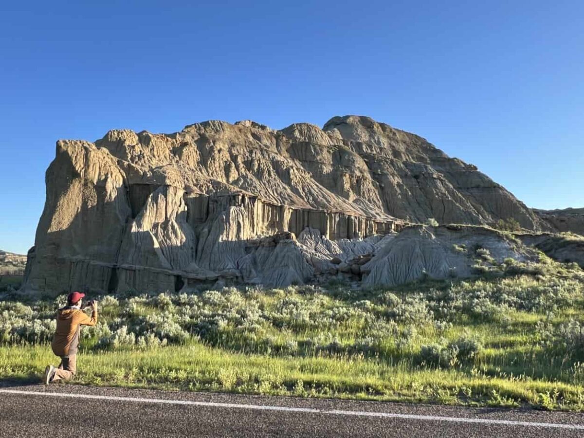Scott McConkey, travel writer and founder of the Miles with McConkey Travel Blog, kneels down to take photos in Theodore Roosevelt National Park, ND.