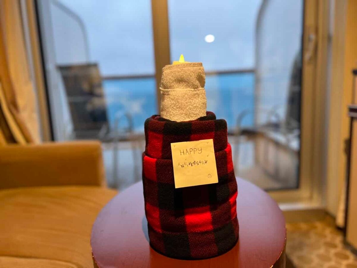 A sticky note with the words "Happy Anniversary" is attached to a rolled blanket that looks like a lit candle.