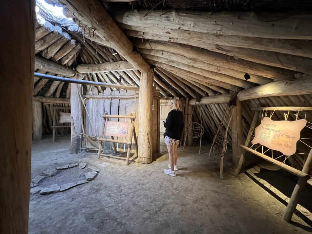 A woman stands inside an earth lodge within On-A-Slant Village in North Dakota