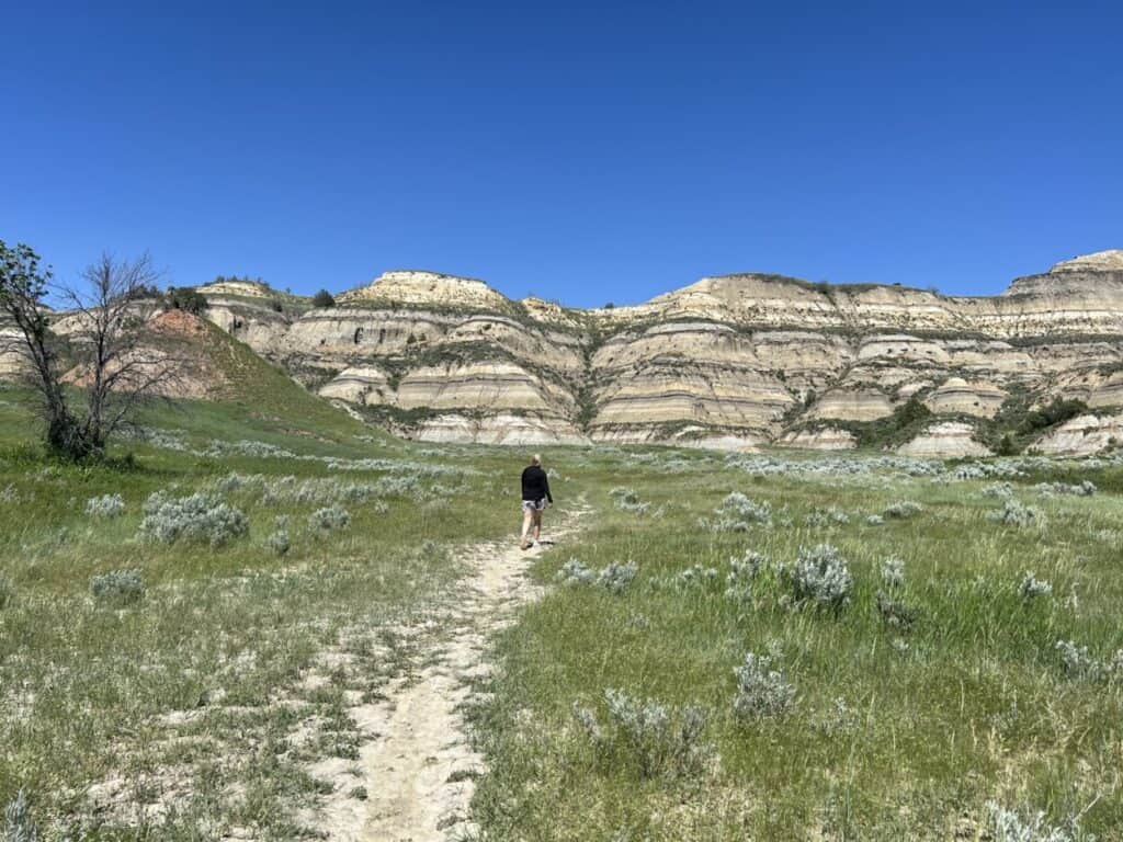 Julie McConkey, co-founder of the Miles with McConkey Travel Blog, walks toward the badlands formations in Theodore Roosevelt National Park, ND.