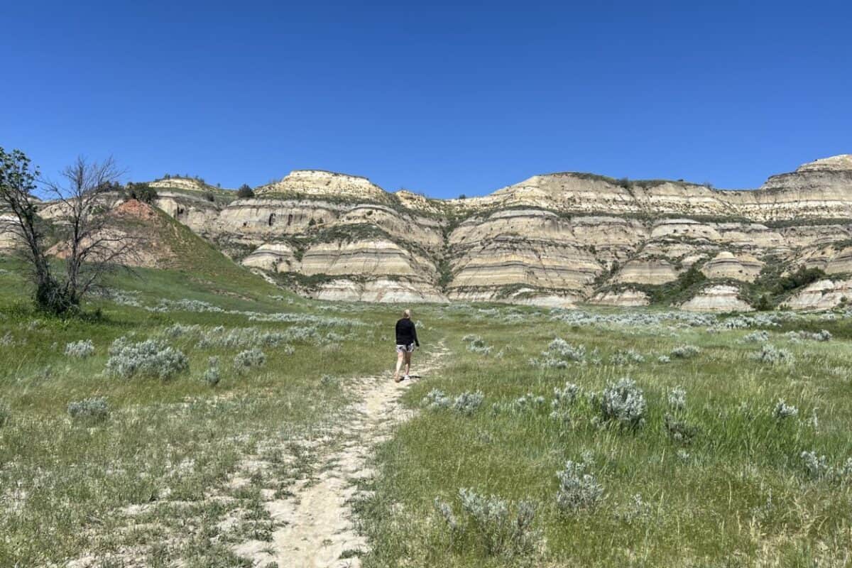 Julie McConkey, co-founder of the Miles with McConkey Travel Blog, walks toward the badlands formations in Theodore Roosevelt National Park, ND.
