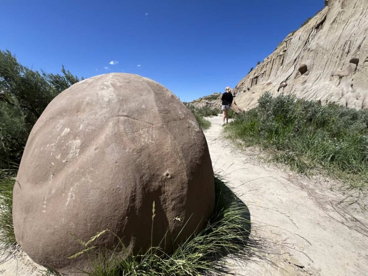A woman walks past a cannonball concretion in Theodore Roosevelt National Park