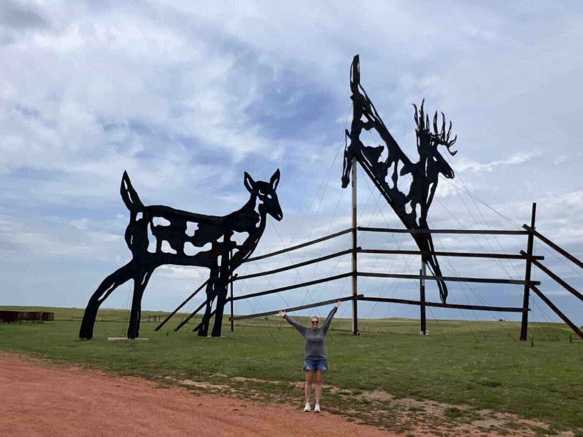 A roadside attraction with giant metal deer jumping a fence in ND.