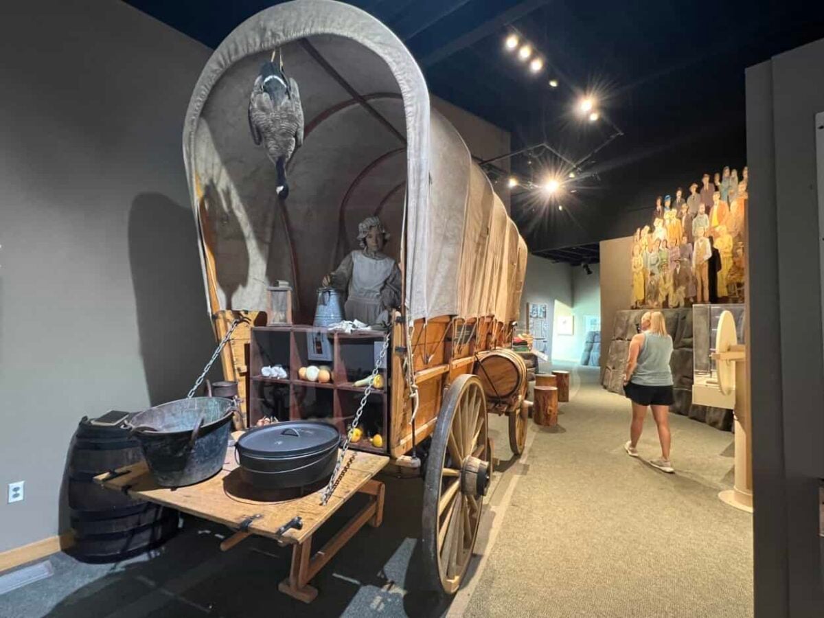 A woman walks past a Conestoga wagon exhibit in the Three Islands Crossing State Park visitor center, Glenns Ferry, Idaho