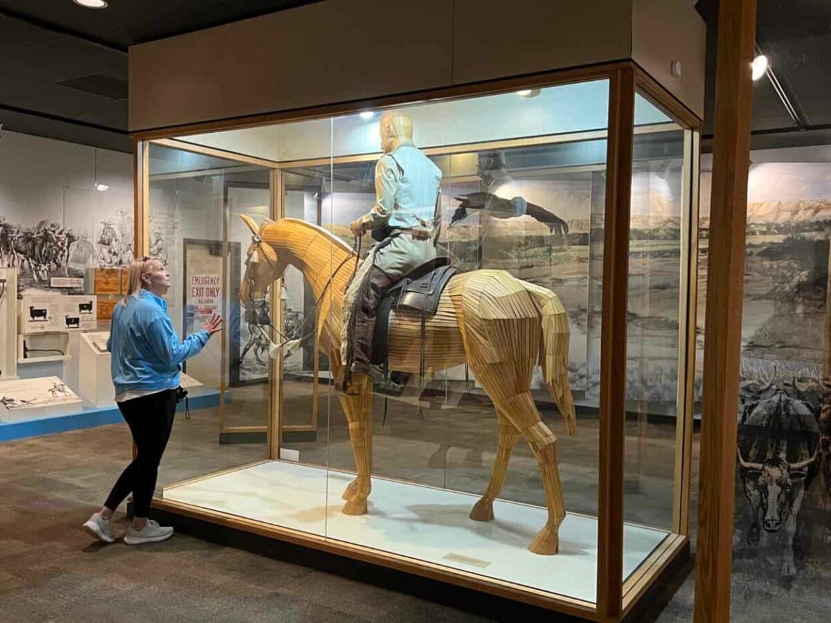 A woman looks at an exhibit with a man riding a horse in the Theodore Roosevelt National Park Visitor Center