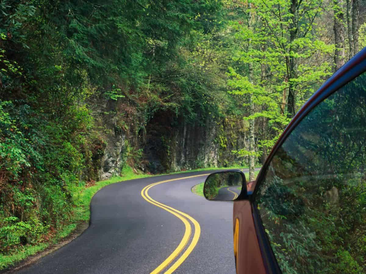 A car drives a winding road through the Great Smoky Mountains