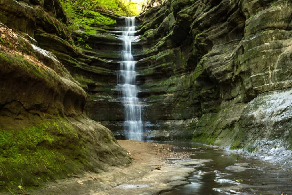 Water flows down a moss-covered sandstone wall