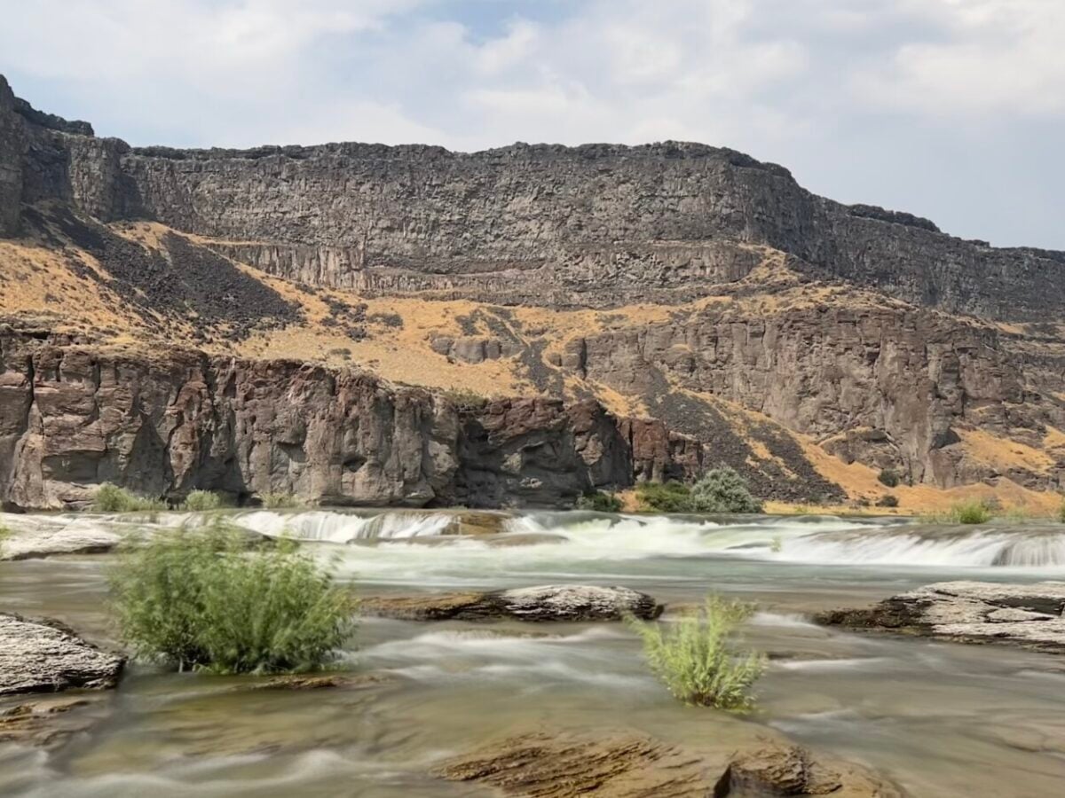 A series of small waterfalls spill over a rocky ledge slightly above the Snake River, Idaho.