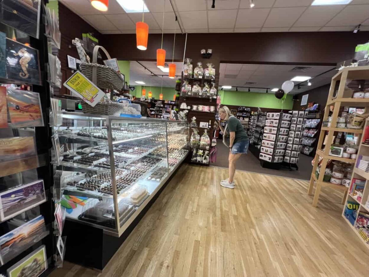 A woman peers at a glass case of chocolates.