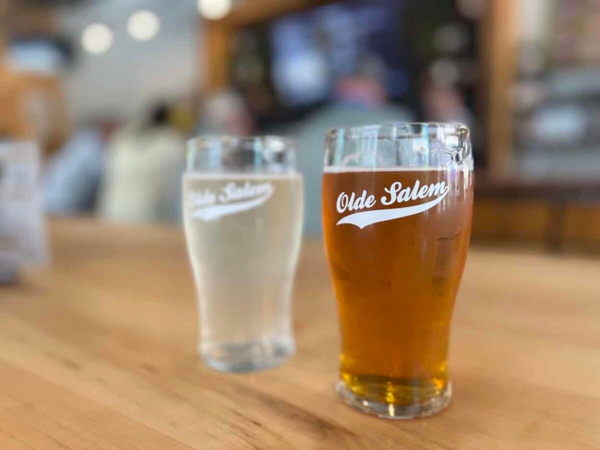 Two glasses of beer sit on a table.