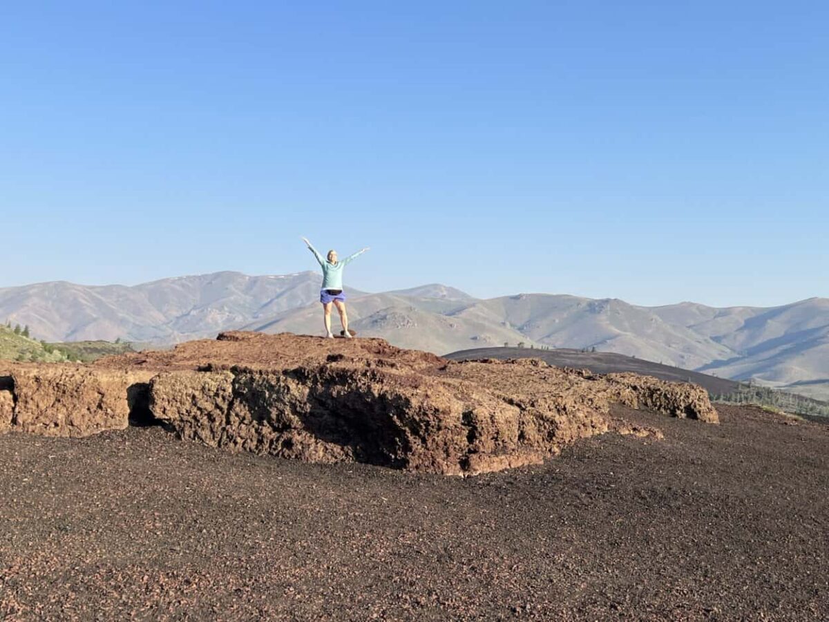 A woman raises her arms in triumph after climbing to the top of Inferno Cone.