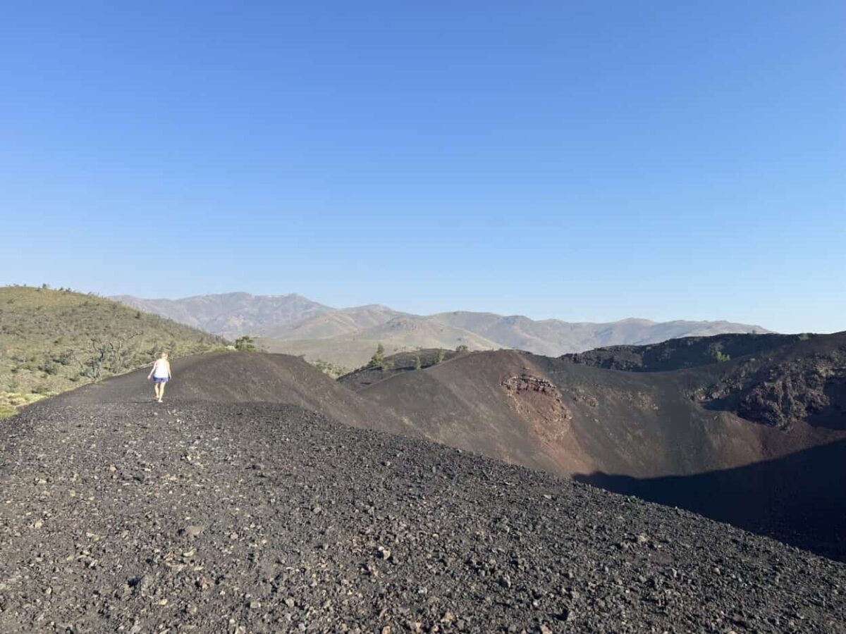 A woman walks along the edge of a volcano crater.