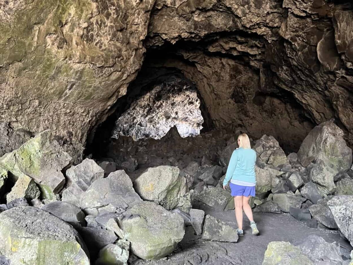 A woman explores a cave full of large rocks