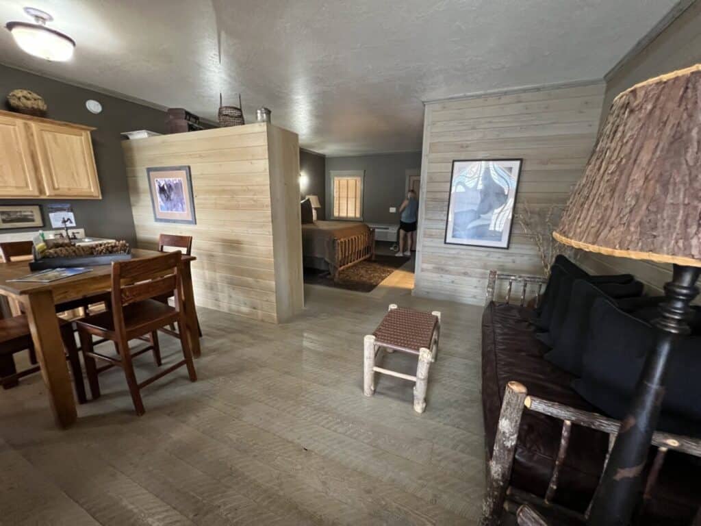 Interior of the Almo Inn: a kitchen table with chairs, a couch with pillows, and a be in the background.