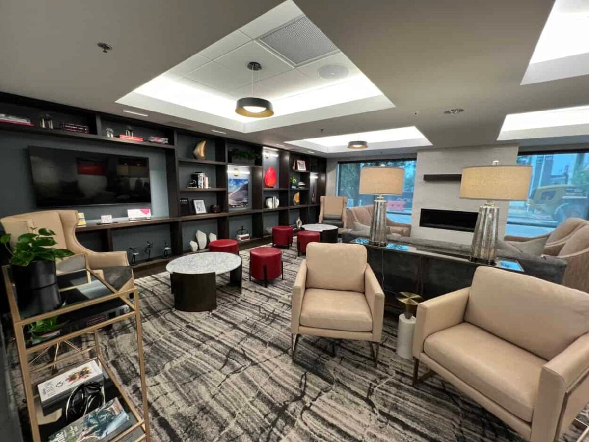Comfortable lounge area in a boutique hotel with assorted chairs and a long set of shelves and a large television on the wall.
