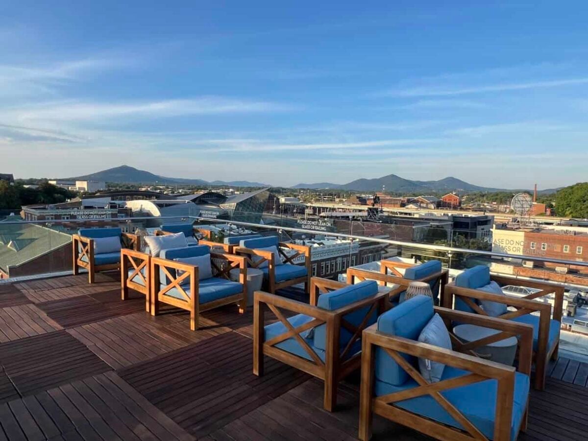 Chairs with blue cushions sit on a rooftop overlooking Roanoke and the Blue Ridge Mountains.