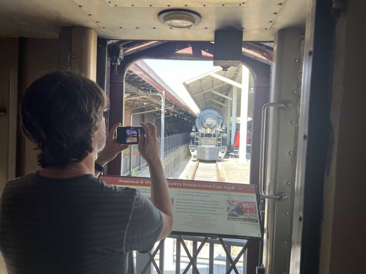Scott McConkey, travel writer and the founder of the Miles with McConkey Travel Blog, takes a picture of a locomotive from a railcar.
