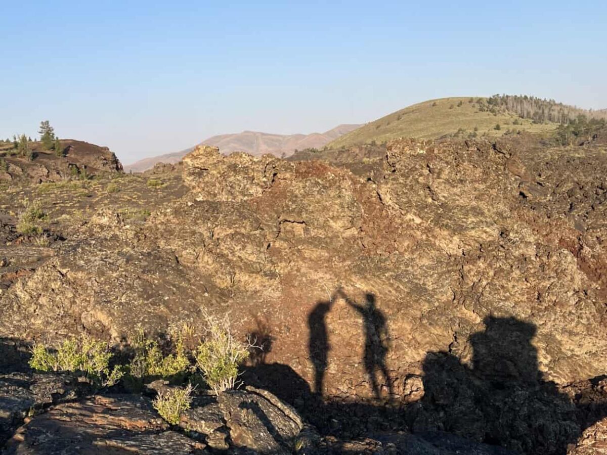 Scott McConkey and Julie McConkey of the Miles with McConkey Travel Blog perform their signature shadow high five at Craters of the Moon National Monument and Preserve in Idaho