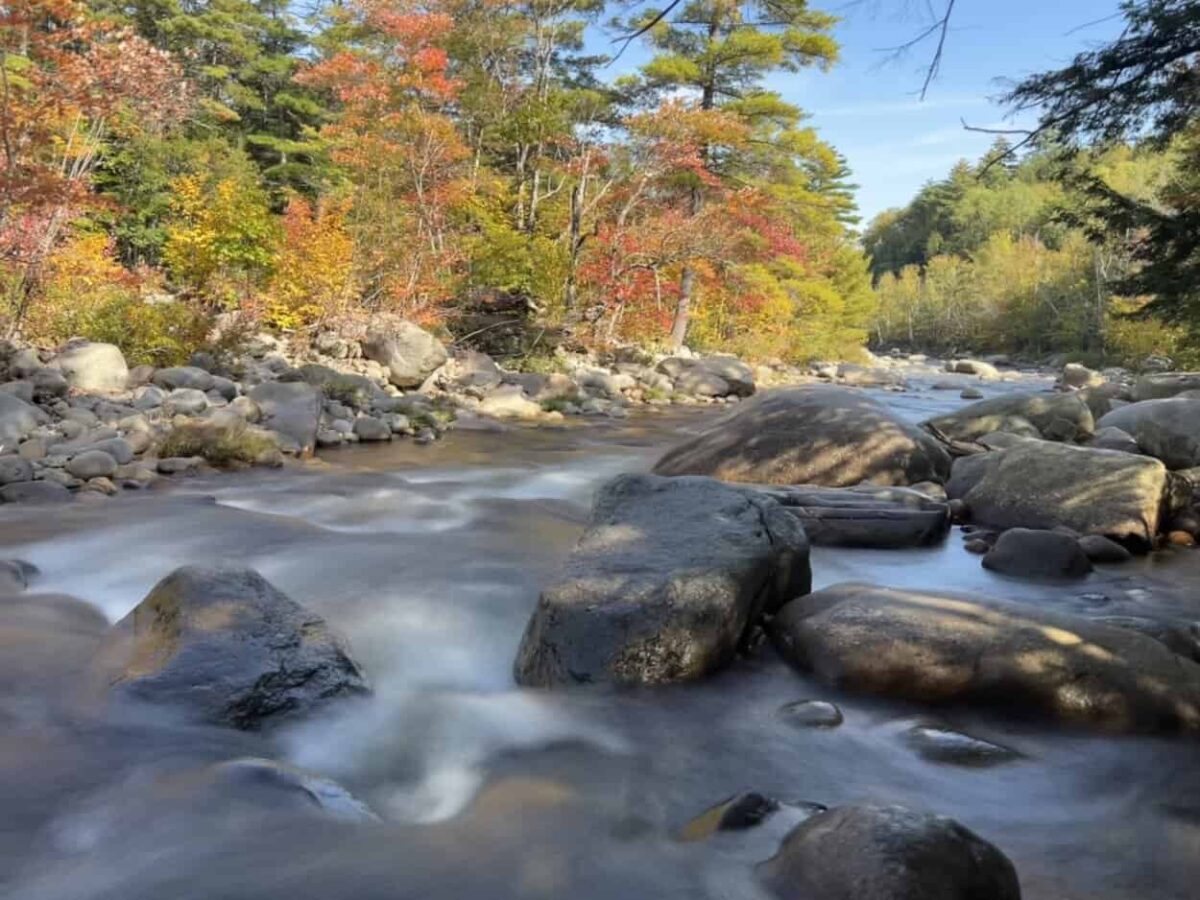Water flows over large rocks in a river.