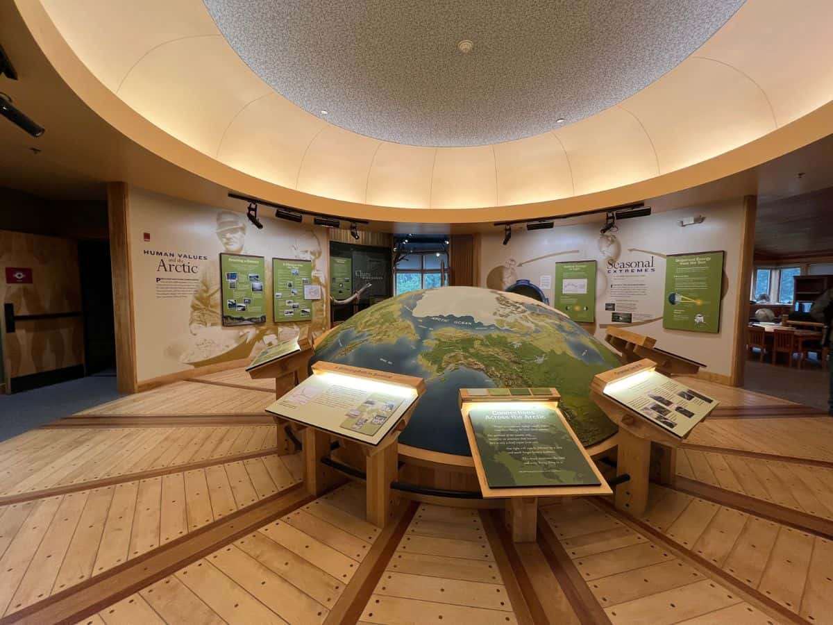 A rounded world map showing the Arctic Circle sits in the middle of a room with display panels about the Arctic in the background.