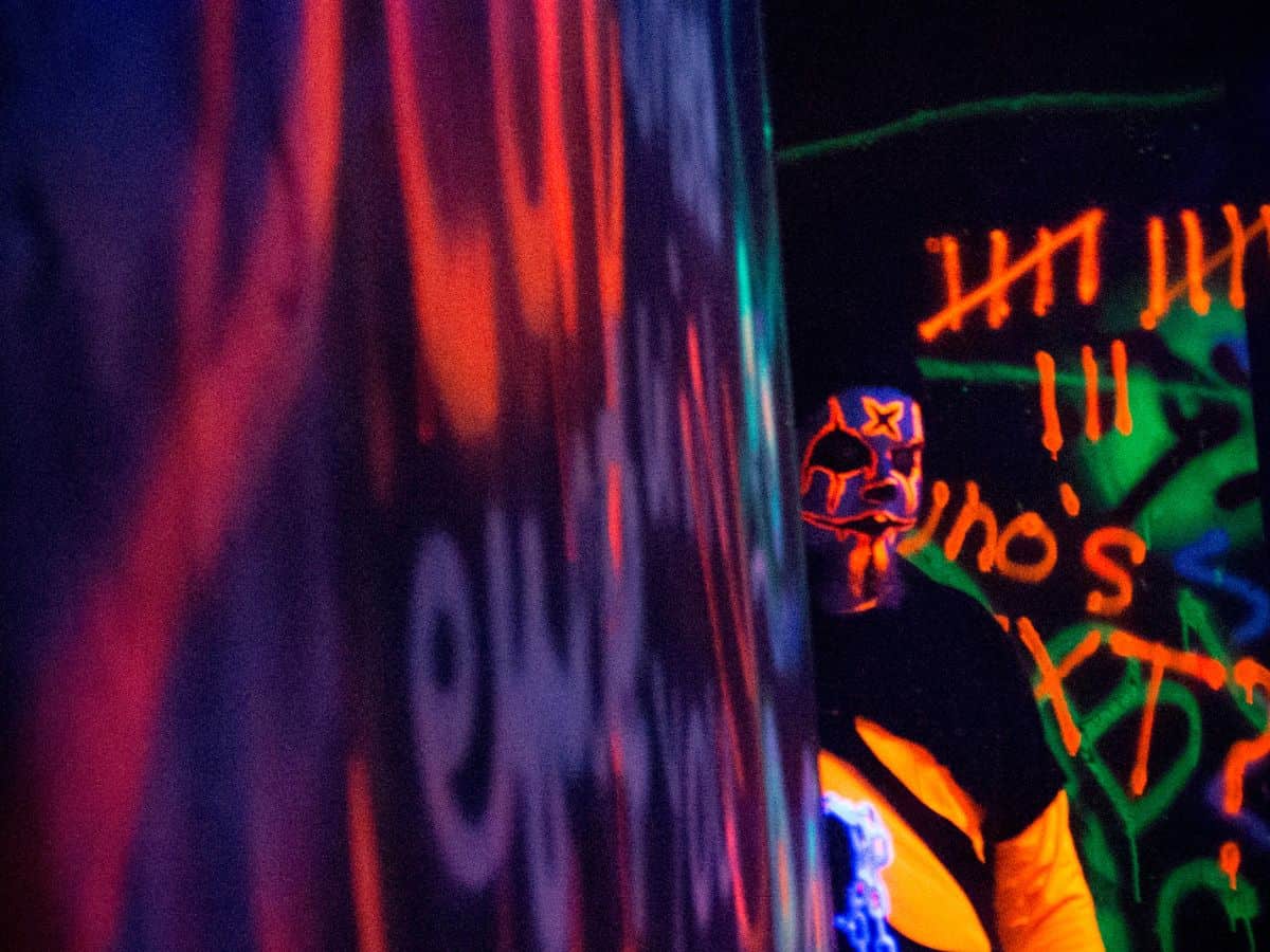 A man in neon orange and purple clothing and face paint gets ready to scare visitors in a haunted house at Haunted Fort, Mandan, North Dakota.