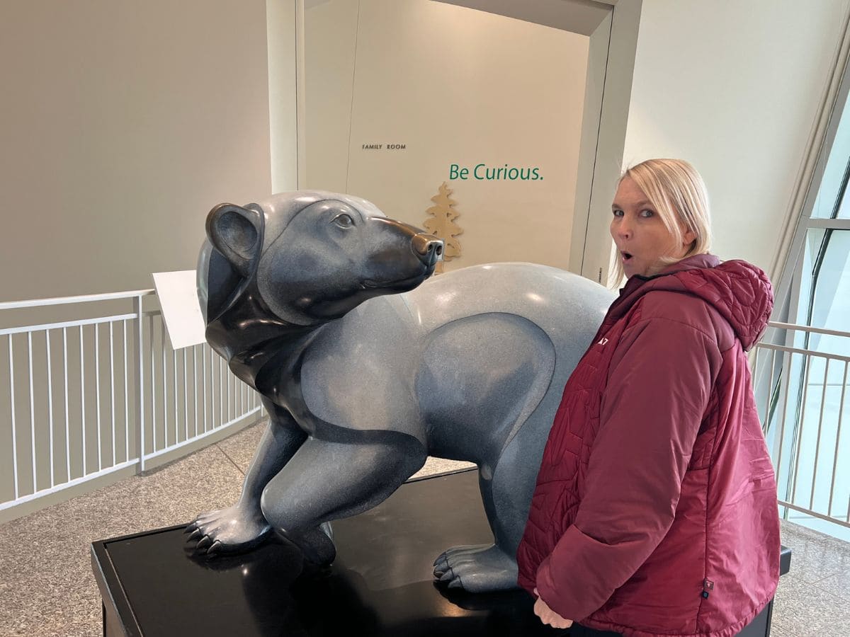 A woman shows a surprised look on her face while looking at a bear sculpture at the University of Alaska Museum of the North in Fairbanks.