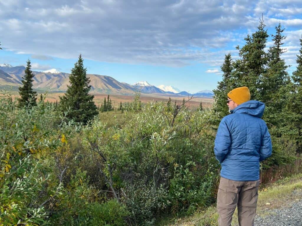 A man pauses to take in the view of mountains on the horizon in Denali National Park, Alaska.