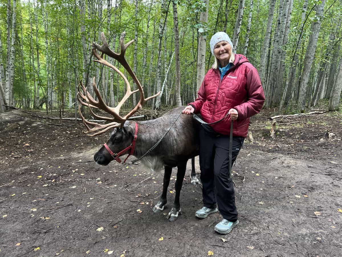A woman poses for a picture with a reindeer at Running Reindeer Ranch in Fairbanks, AK.