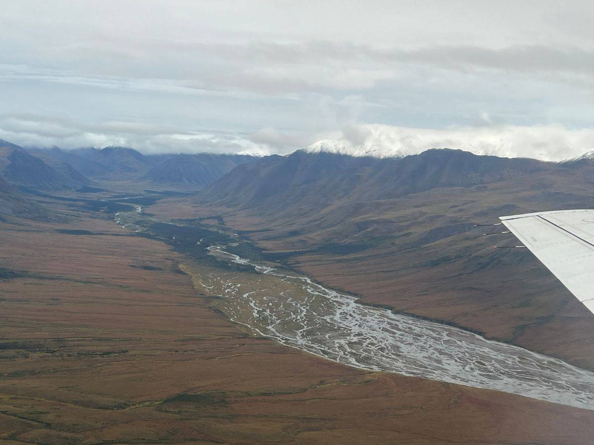A river runs through a valley between soaring mountains in Gates of the Arctic National Park Alaska.