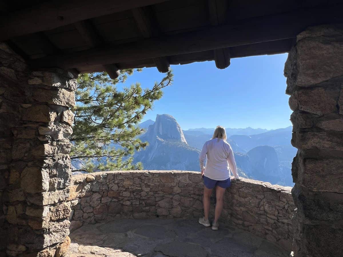 A woman looks at Yosemite National Park's iconic granite domes from a lookout tower in Glacier Point.