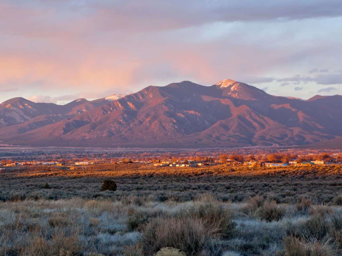 Clouds hang above a mountain range with a few peaks covered with snow