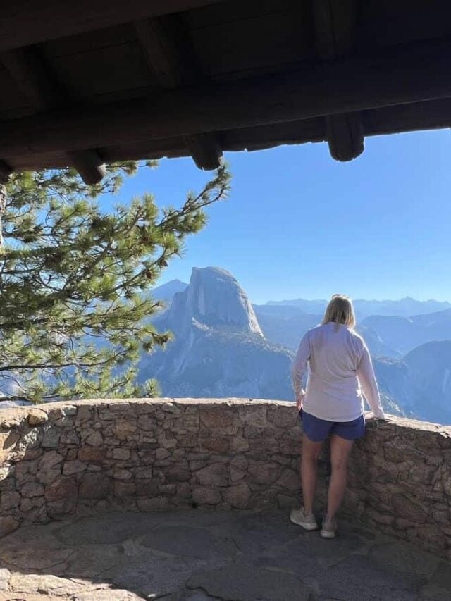 A woman looks at Yosemite National Park's iconic granite domes from a lookout tower in Glacier Point.